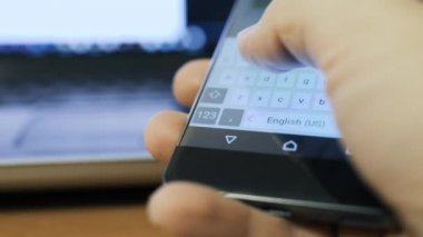 Bir smartphone aygıtında manifatura kişi. Arka plan üstünde laptop