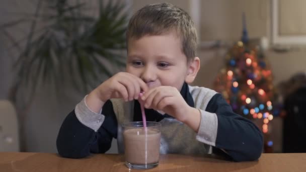 Niño bebiendo una bebida sabrosa a través de una paja en casa — Vídeos de Stock