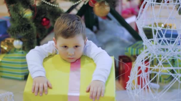 Mutlu çocuk yeni yıl hediyeleri istemiyorum ve üzücü. Noel ağacının altında oturan çocuk — Stok video