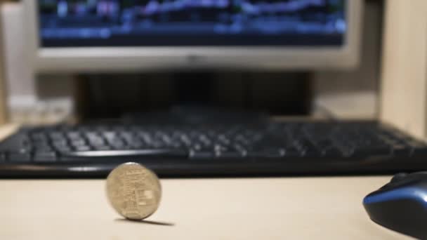 Bitcoin draait tegen de achtergrond van een monitor en toetsenbord — Stockvideo