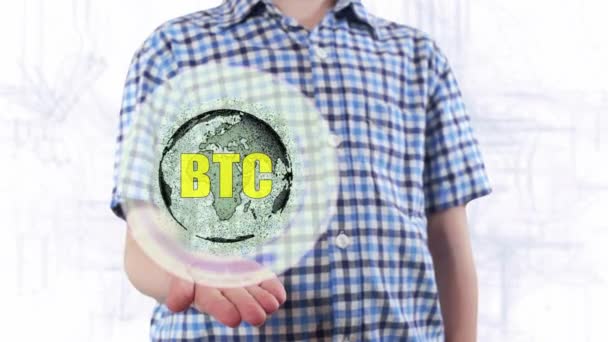 Young man shows a hologram of the planet Earth and text BTC — Stock Video