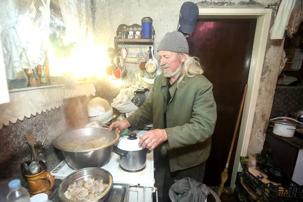 Velho homem fervendo carne — Fotografia de Stock