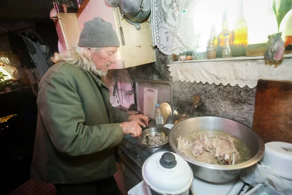 Vieil homme cuisinant de la viande de porc — Photo