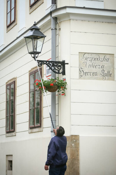 Человек зажигает уличную лампу
