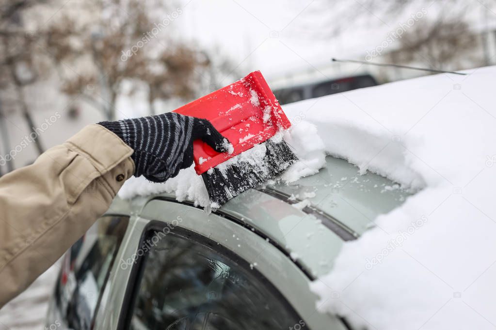 Cleaning snowy car in winter