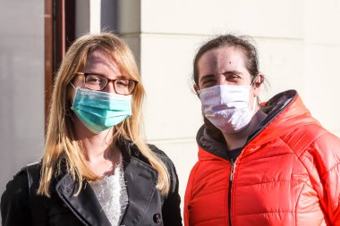 Zagreb, Hırvatistan - 19 Mart 2020: Zagreb sokaklarında yaşayan insanlar korona virüsü krizi nedeniyle koruyucu maskeler takıyorlar. İki genç bayan koruyucu maskelerle sokakta poz veriyor..
