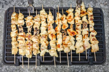 Tavuk eti ve mantar şiş barbeküde ızgara yapıyor..