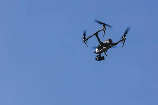 Big drone for video recording flying in the air at a clear blue sky.
