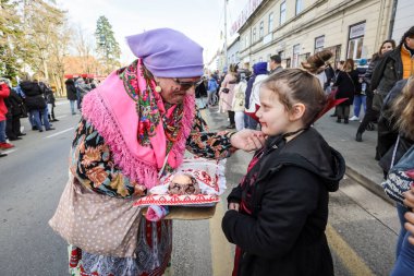 Velika Gorica, Hırvatistan -22 Şubat 2020: Turopoljski Karnavalı sırasında Velika Gorica ana caddesinde karnaval geçidi görülüyor. Halk kostümü giymiş, krampus maskeli, yeni doğmuş bebekleri taşıyan bir kadın..