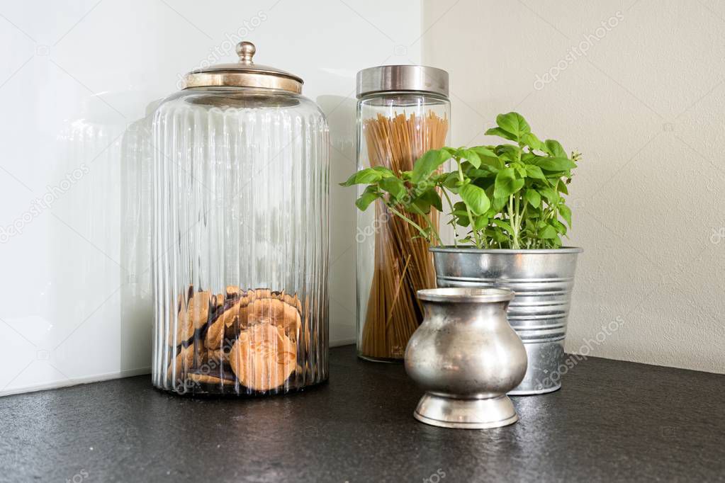 Close up of the kitchen objects - cookie jar, herbs in flowerpot, jar with pasta, and silver sugar-bowl