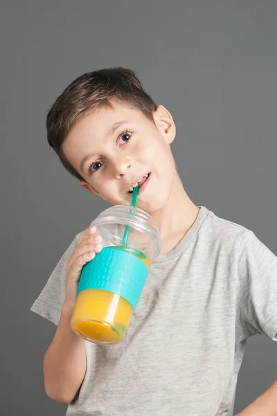 Little funny boy drinking a fresh cola juice through a straw — Stock Photo, Image