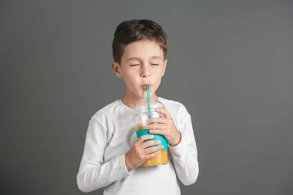 Pequeño chico divertido bebiendo un jugo de cola fresca a través de una paja —  Fotos de Stock