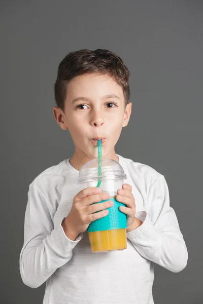 Little funny boy drinking a fresh cola juice through a straw — Stock Photo, Image