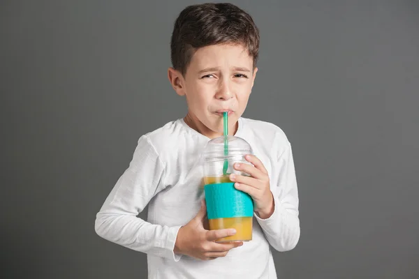 Little funny boy drinking a fresh cola juice through a straw — Stock Photo, Image