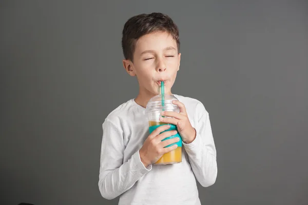 Little funny boy drinking a fresh cola juice through a straw — Stock Photo, Image