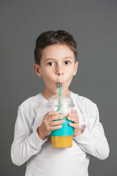 Little funny boy drinking a fresh cola juice through a straw — Stock Photo, Image