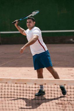 Tenis kortunda yakışıklı genç adam. Tenis oynuyor dostum. Adam vurma tenis topu