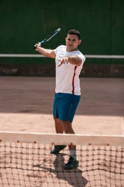 Tenis kortunda yakışıklı genç adam. Tenis oynuyor dostum. Adam vurma tenis topu