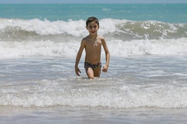 Eğleniyor tropik sahilde güneşli bir günde altı yaşında bir çocuk