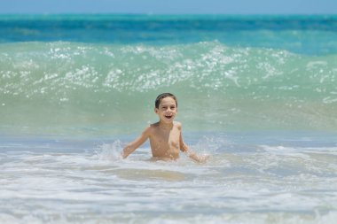 Eğleniyor tropik sahilde güneşli bir günde altı yaşında bir çocuk