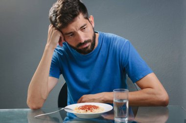 Portrait of man with no appetite in front of the meal. Concept o