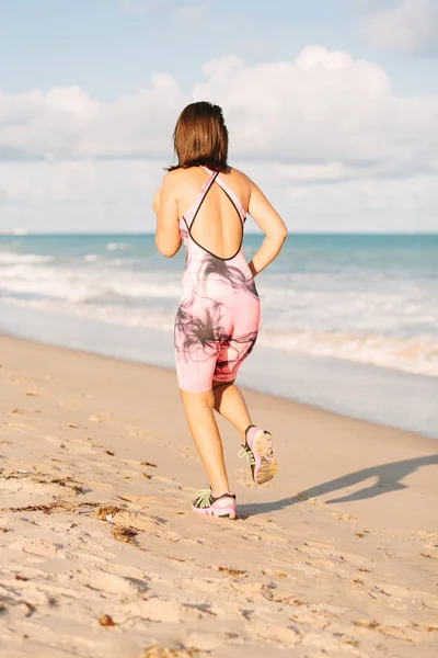 Koşan kadın. Kadın koşucu plajda antrenman yaparken koşuyor.