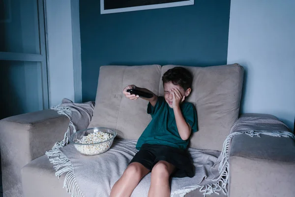 Scared child watching scary movie on tv, sitting on the couch at night — Stock Photo, Image