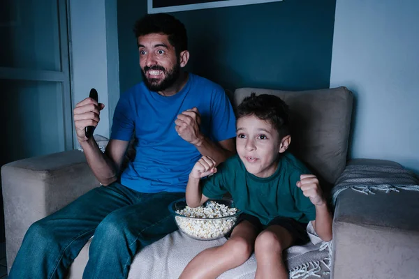 Ayah dan anak menonton TV dan bersorak di malam hari — Stok Foto