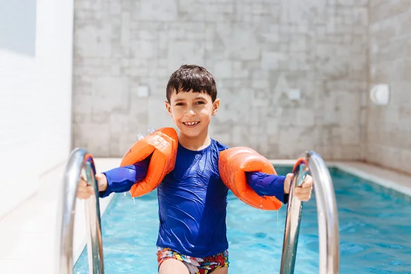 Süßer kleiner Junge im Badeanzug mit Armschwimmen im Pool — Stockfoto
