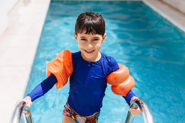 Süßer kleiner Junge im Badeanzug mit Armschwimmen im Pool — Stockfoto