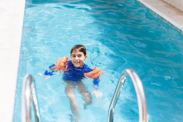 Süßer kleiner Junge im Badeanzug mit Armschwimmen im Pool — Stockfoto