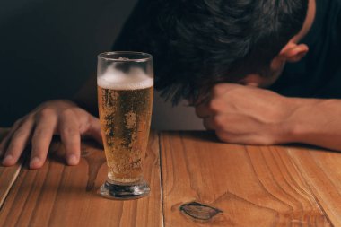 Alkolizm kavramı. Masada bir bardak bira karanlık bir odada ile üzgün adam.
