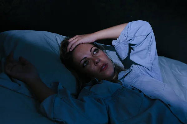 Sleep disorder, insomnia. Young blonde woman lying on the bed awake — Stock Photo, Image