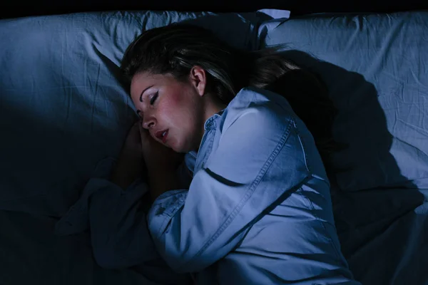 Mulher pacificamente dormindo na cama à noite — Fotografia de Stock