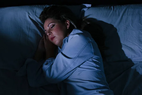 Женщина мирно спит в постели ночью — стоковое фото