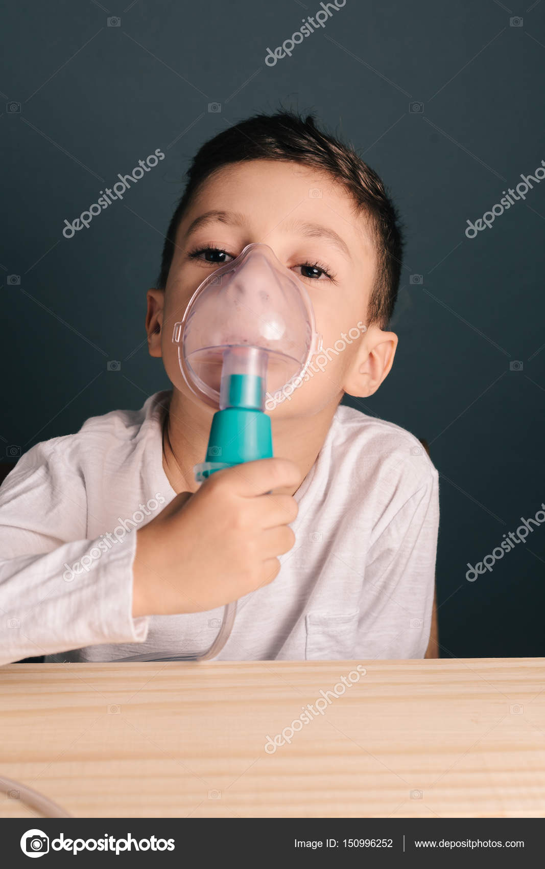 Beautiful sick boy inhalation therapy by the mask of inhaler. Image of a cute with respiratory problem or asthma. View of nebulizer with smoke from mask Stock Photo by ©kleberpicui