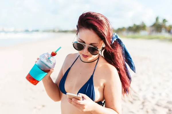 Joven pelirroja bebiendo cóctel de fresa en la playa — Foto de Stock
