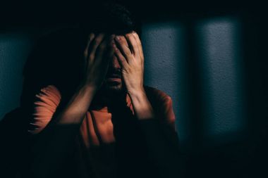 Mahkum adam karanlık hücreye yüz utanç ile gizleme