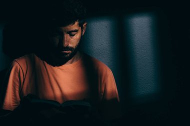 Mahkum adam karanlık hücreye bir kitap ya da İncil okuma
