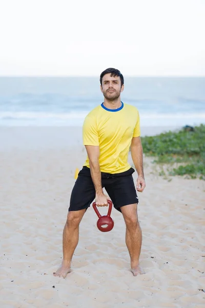 Hombre brasileño levantando pesadas pesas en una playa durante el entrenamiento —  Fotos de Stock