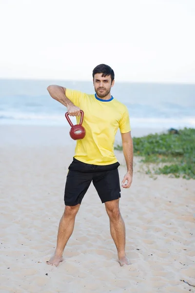 Hombre brasileño levantando pesadas pesas en una playa durante el entrenamiento —  Fotos de Stock