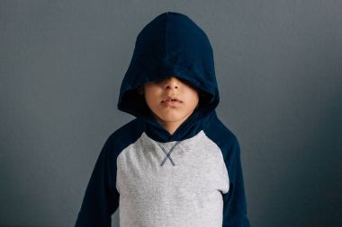 Gri arka plan üzerinde bir başlık takıyor üzgün bir çocuk portresi