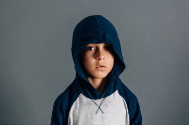 Gri arka plan üzerinde bir başlık takıyor üzgün bir çocuk portresi