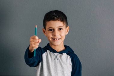 Bir kalem tutan gülümseyen Brezilyalı çocuk portresi