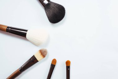 Makyaj ürünleri ve beyaz arka planda fırçalar