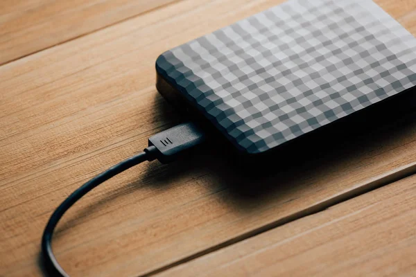 Draagbare externe harde schijf met USB-kabel op houten achtergrond. — Stockfoto