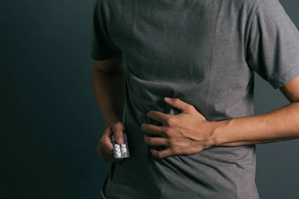 Joven con paquete de pastillas siente dolor de estómago — Foto de Stock