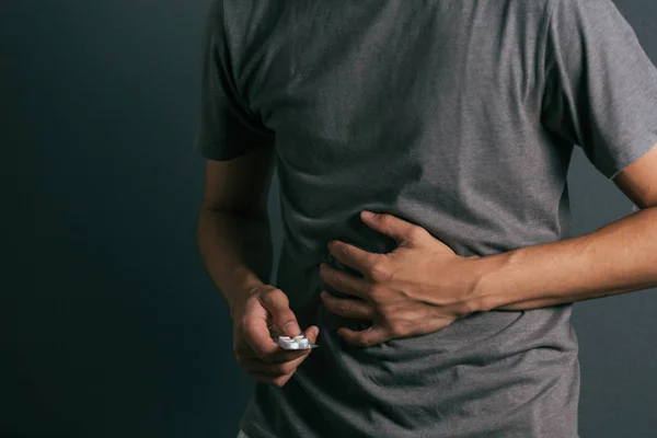 Mladý muž s balení pilulek cítí bolest žaludku — Stock fotografie