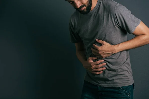 Jonge man lijdt aan maag pijn staande — Stockfoto