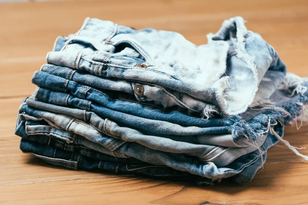 Fashionabla kläder. hög med jeans på en trä bakgrund — Stockfoto